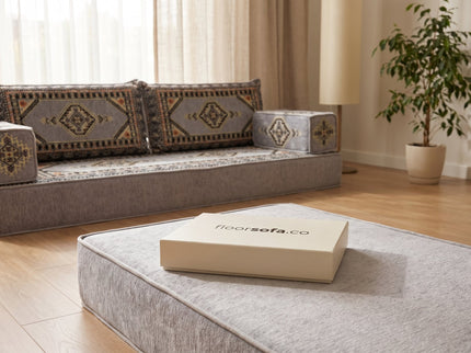 Closed Floorsofa sample box resting on a thick gray floor sofa cushion for scale