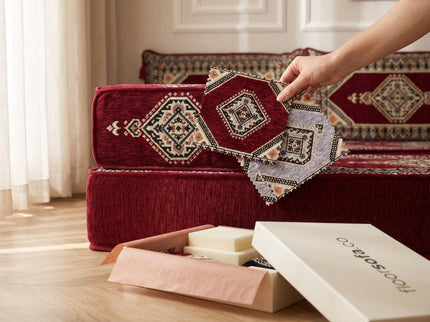 Holding maroon and gray swatches against a maroon floor sofa to compare the fabric